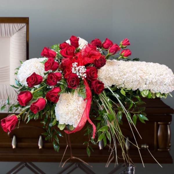 Red roses and white floral spray arranged on a stand
