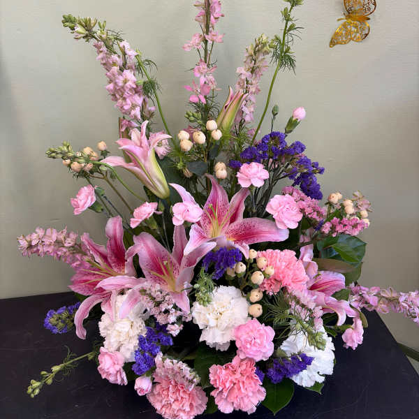 Pink lilies and carnations arranged with purple filler flowers