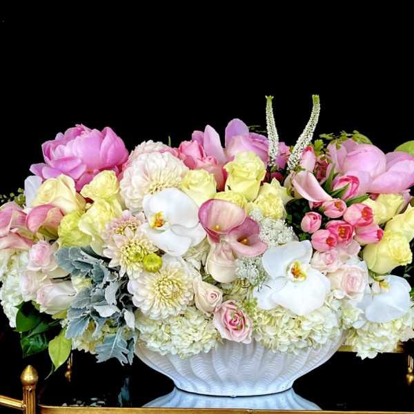 Large pastel floral arrangement in a white pedestal vase