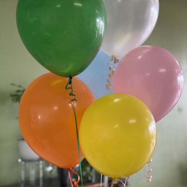 Cluster of colorful helium balloons in green, white, pink, orange, and yellow