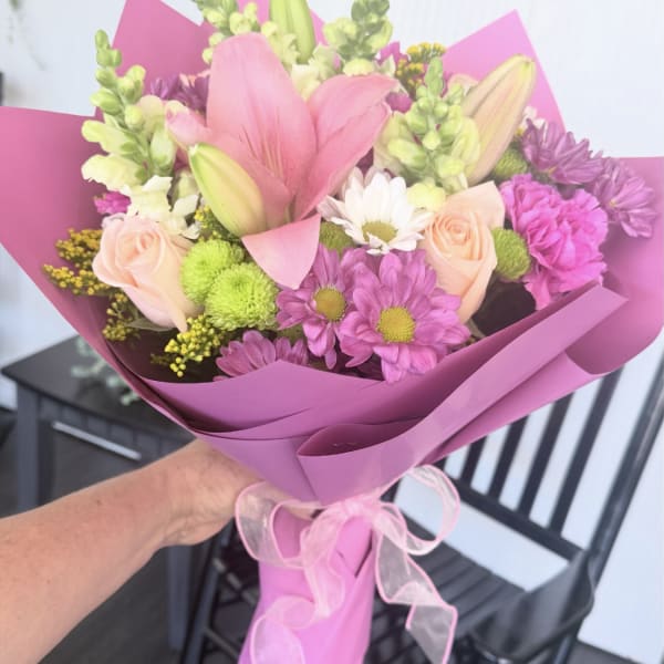 Pink and peach mixed bouquet wrapped in magenta paper with a ribbon
