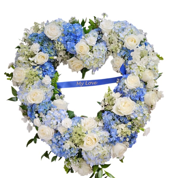 Heart-shaped floral wreath of white roses and blue hydrangeas with a blue ribbon
