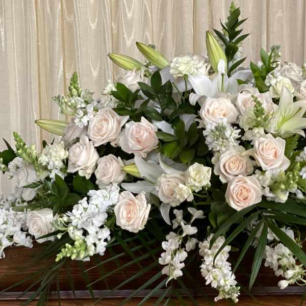 Large white and blush floral casket spray with lilies and roses