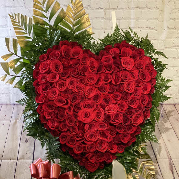 Heart-shaped red rose arrangement with ribbon and greenery