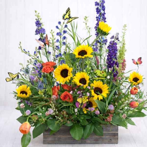Mixed bouquet with sunflowers, orange roses, and purple blooms in a wooden box