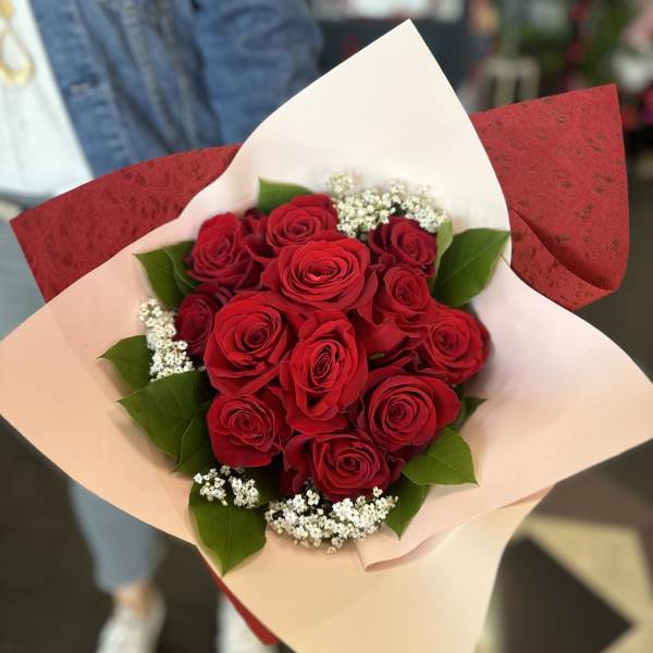 Bouquet of red roses with white filler flowers in pink and red wrap