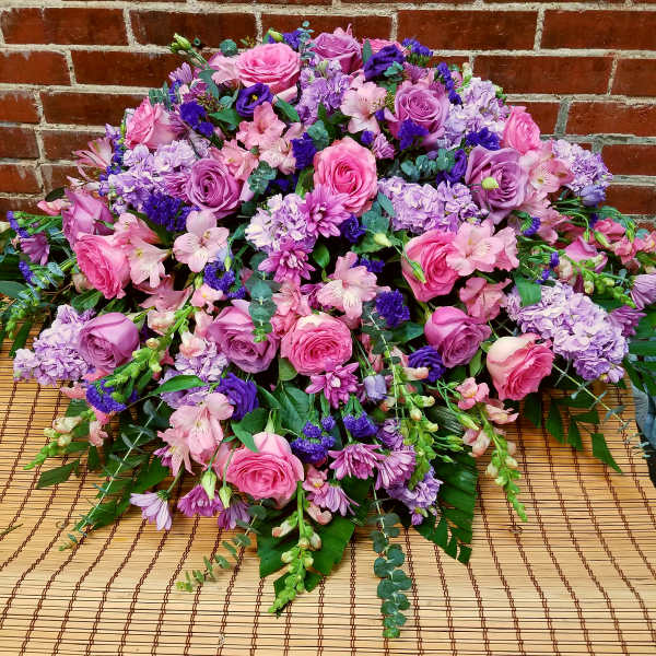Large pink and purple floral arrangement with roses and mixed blooms