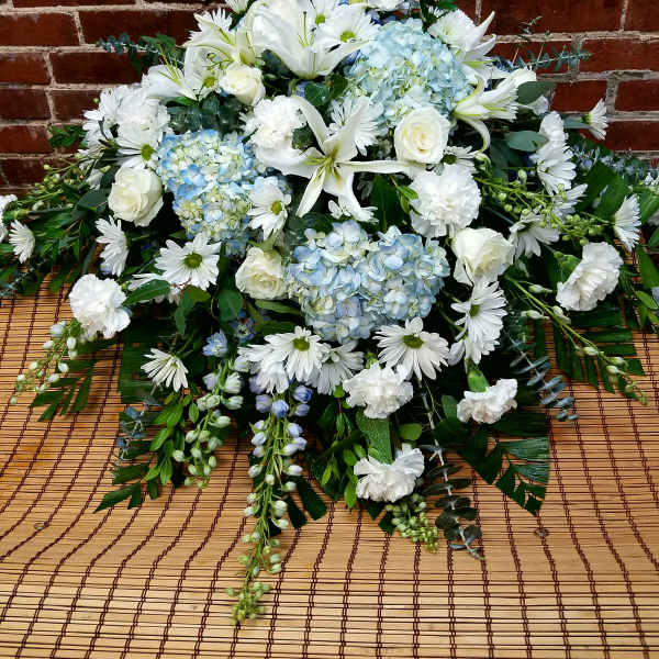 White lilies, roses, daisies, and blue hydrangeas in a low arrangement