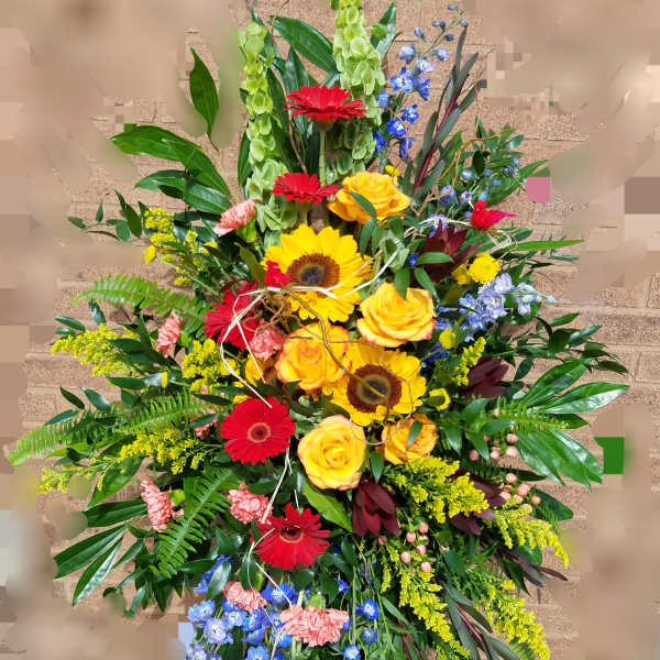 Tall mixed floral spray with red gerberas, yellow roses, and blue flowers