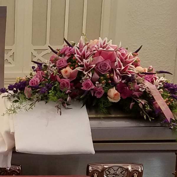 Large pink and purple floral casket spray with roses and lilies