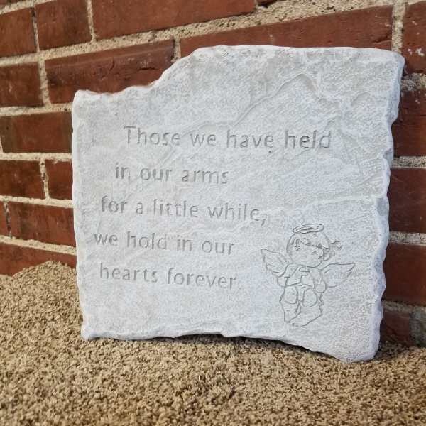 A white memorial stone plaque with an angel engraving and engraved text.