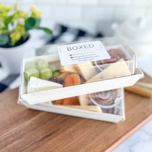 Two stacked clear-lidded snack boxes with fruit and cheese