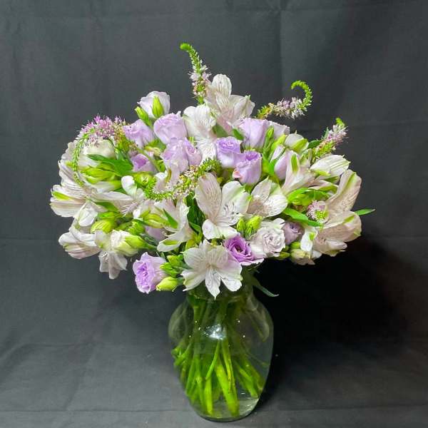 Lavender and white flowers arranged in a clear glass vase