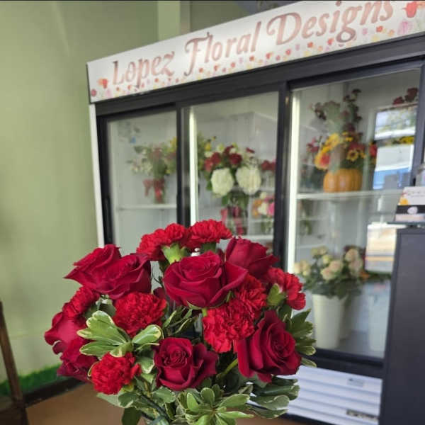 Red roses and carnations in a clear glass vase