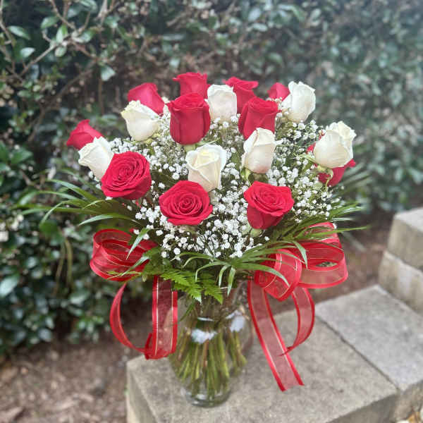 Bouquet of red and white roses in a glass vase with a red ribbon
