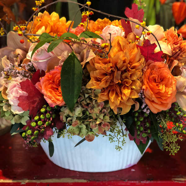 Orange and pink floral arrangement in a white vase