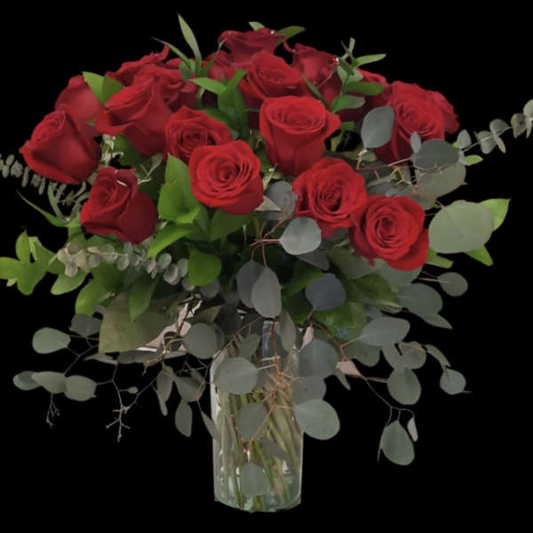 Bouquet of red roses in a clear glass vase with eucalyptus