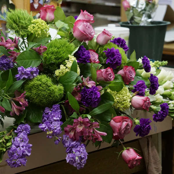Mixed bouquet with pink roses, purple flowers, and green pom-pom blooms
