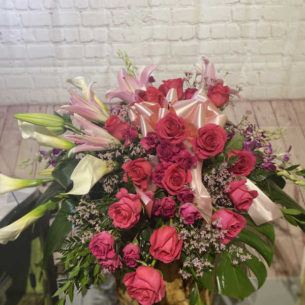 Pink roses and lilies arranged with a satin bow.