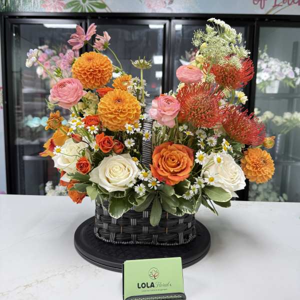 Basket arrangement of orange, pink, and white flowers