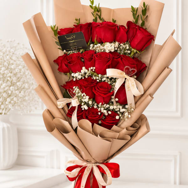 Bouquet of red roses wrapped in tan paper with ribbon