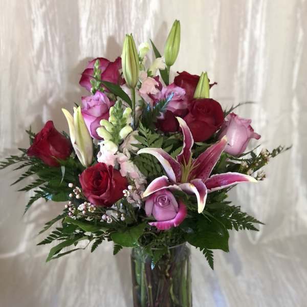 Bouquet of red and pink roses with lilies in a glass vase