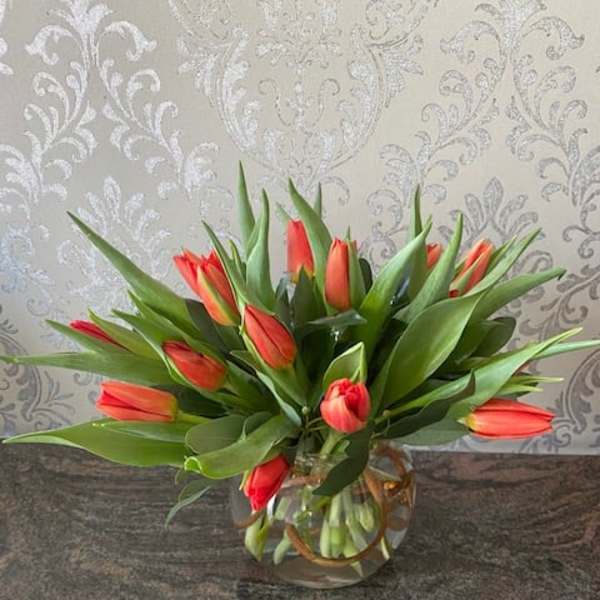 Orange tulips arranged in a clear glass vase