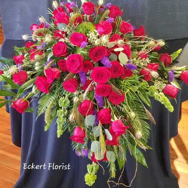 Large red rose arrangement with purple accents and mixed greenery