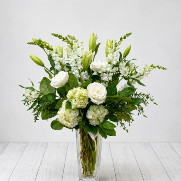 White flowers arranged in a clear glass vase with green accents
