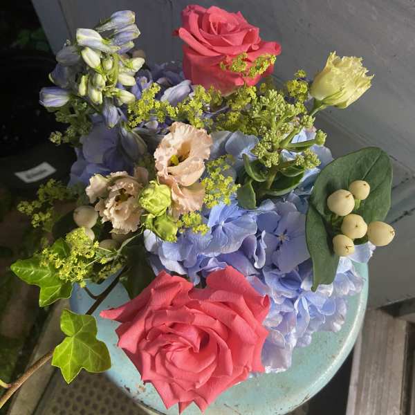 Bouquet of pink roses, blue hydrangea, and pale blooms with berries