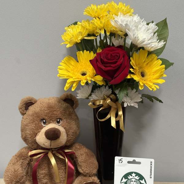 Bouquet of yellow and white flowers in a black vase beside a teddy bear