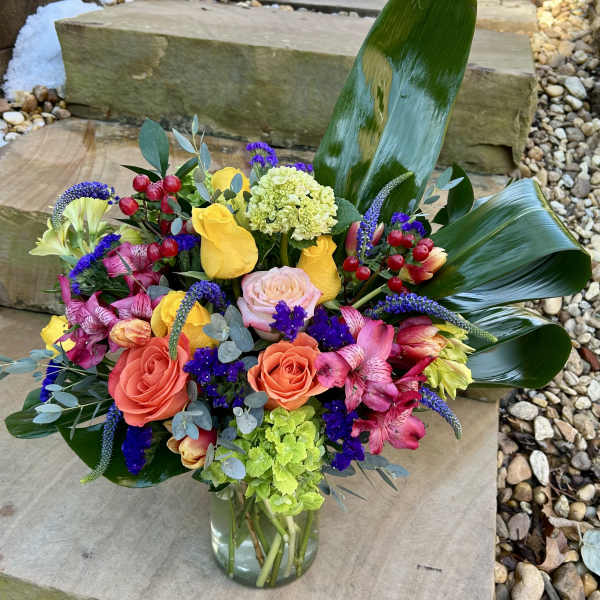 Colorful mixed bouquet in a clear glass vase with roses and alstroemeria