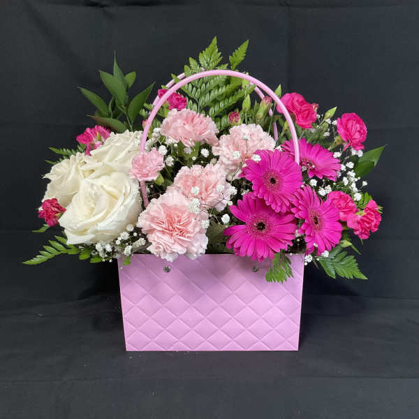 Pink and white flowers arranged in a pink handled gift box