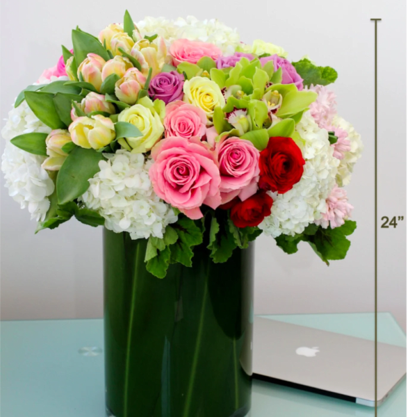 Mixed pink, white, and red roses in a tall green vase