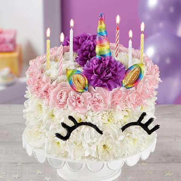 Unicorn-themed cake decorated with flowers and lit candles