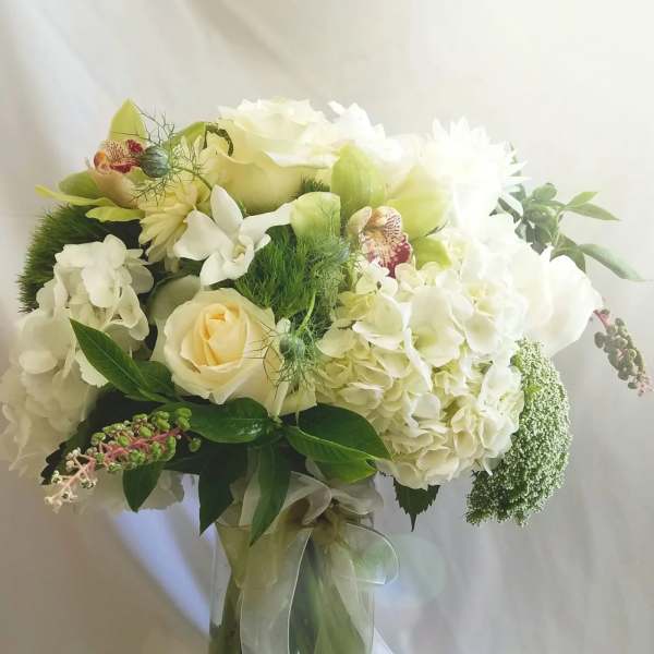 White and pale green bouquet in a glass vase with ribbon