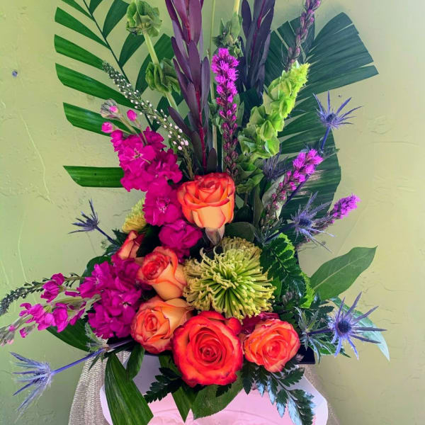 Tall tropical bouquet with orange roses, magenta blooms, and purple accents
