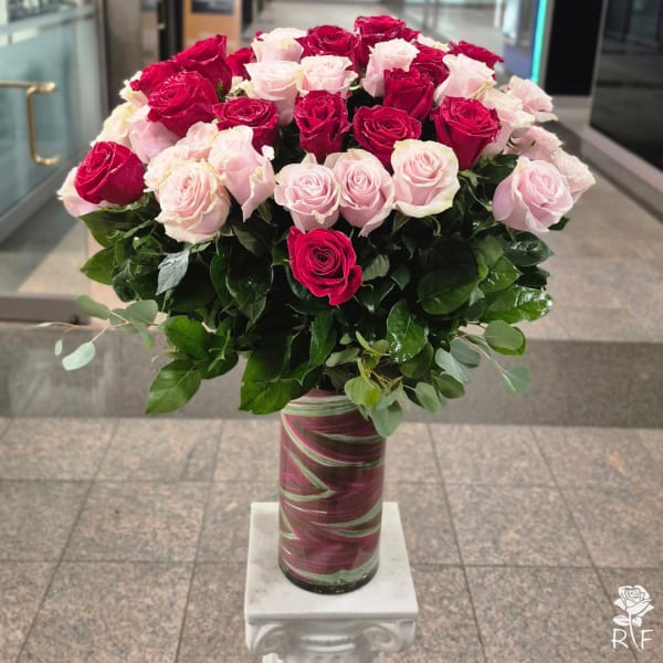 Bouquet of pink and red roses in a tall glass vase
