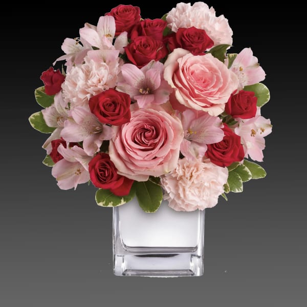 Pink and red roses with pale pink alstroemeria in a clear square vase