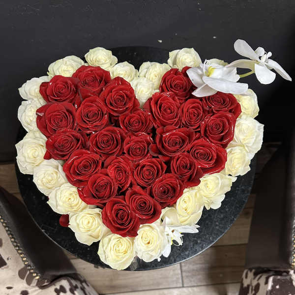 Heart-shaped arrangement of red and white roses with white orchids