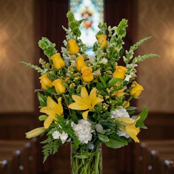 Yellow roses and lilies arranged in a clear glass vase