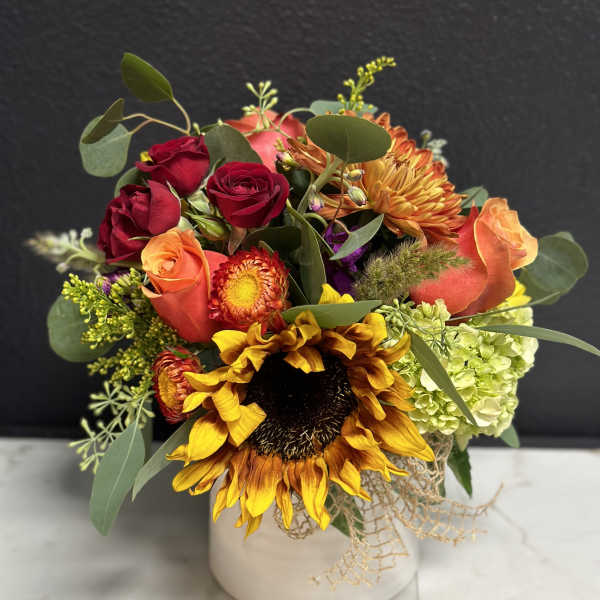 Mixed bouquet with sunflowers, roses, and hydrangea in a white vase