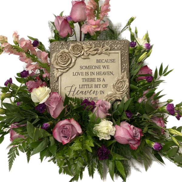 Pink and white roses surround a memorial plaque with a heaven message.