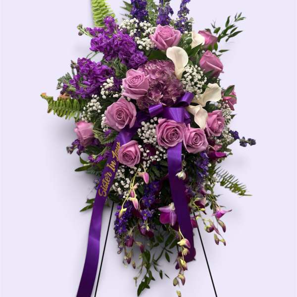 Standing floral spray with purple and pink flowers on a ribboned easel