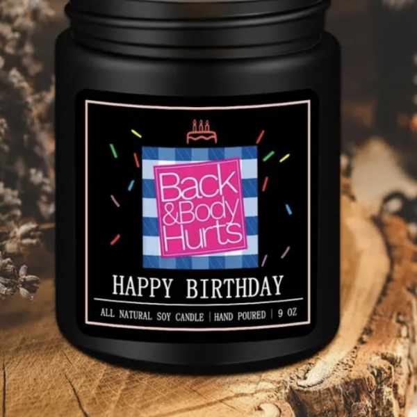 Black jar candle with a lit flame and birthday label
