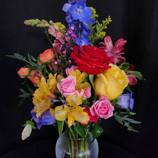 Colorful mixed bouquet in a frosted glass vase with roses and lilies