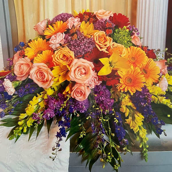 Large colorful floral arrangement with roses, gerbera daisies, and purple blooms