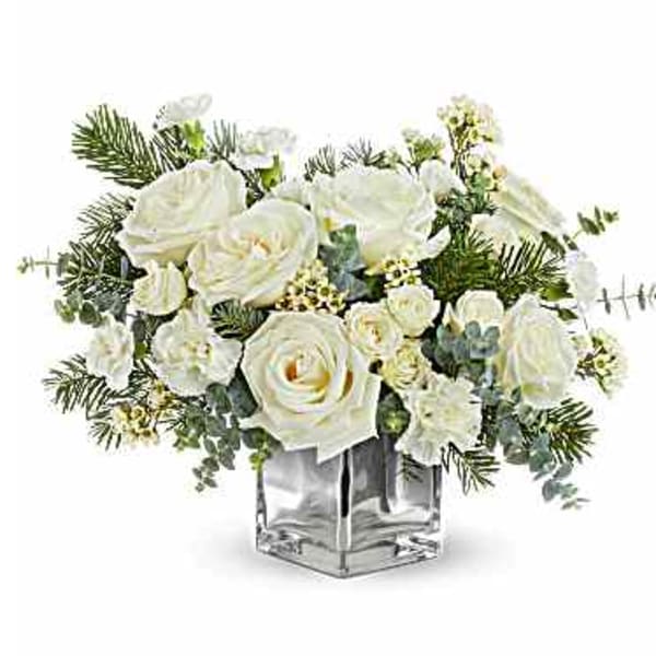 White roses and small white flowers in a clear square vase