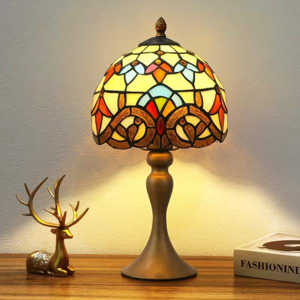Stained-glass table lamp with a bronze base on a wooden surface