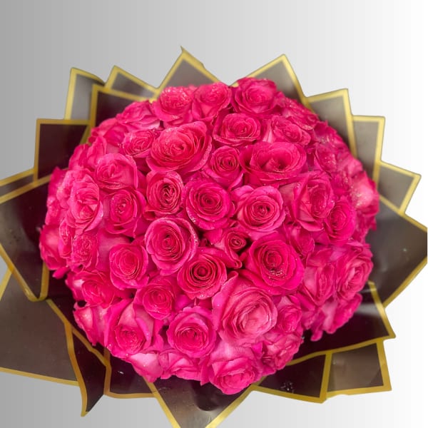 Round bouquet of bright pink roses wrapped in dark paper with gold trim